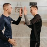 Dois jogadores de vôlei masculino se cumprimentam em comemoração após uma jogada, em uma quadra coberta.