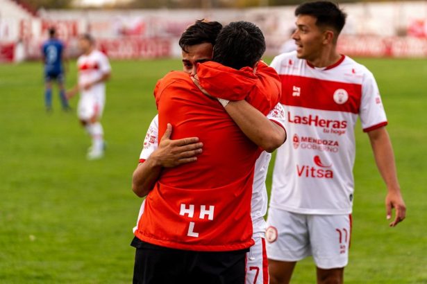 Jogadores de futebol comemoram uma vitória no campo, abraçados e demonstrando alegria.