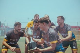 Time de futebol comemora a conquista de um campeonato segurando um troféu em campo