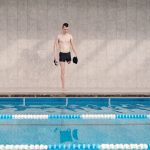 Atleta com prótese em uma perna se prepara para nadar em uma piscina coberta.